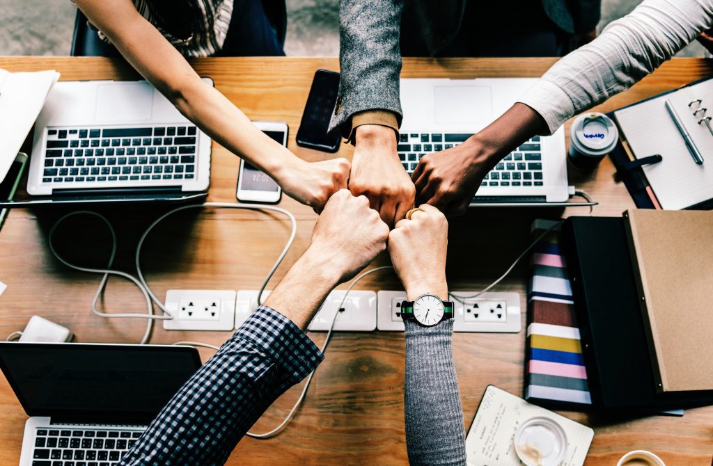 A photo of co-workers fist-bumping, as working with a resume writer is always a collaboration.