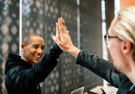 Two colleagues sharing a high five after a job well done - just like you will with your friendly, professional resume writer from Let's Eat, Grandma!