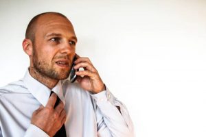 A photo of a businessman on a phone call, clutching his tie and making a nervous face - representative of the anxiety involving in wondering how to ask about salary.