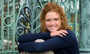 A smiling woman with an ornate gate behind her, an example of a bad background for a LinkedIn headshot.