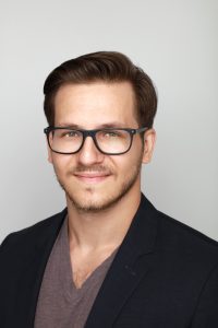 A headshot of a smiling man in glasses and a sportcoat – an example of good attire for a LinkedIn headshot.