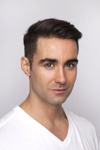 A photo of man against a plain white backdrop, an example of a good background for a LinkedIn headshot.