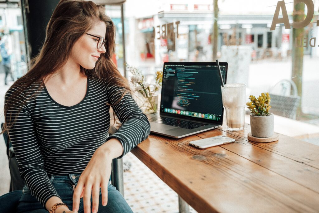 woman at a cafe looking at a laptop with code