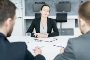 A photo of a woman at a table negotiating with two other professionals, illustrating the negotiations inherent in answering the salary expectations question.