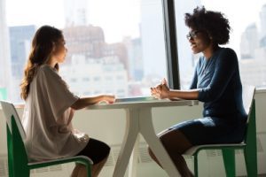 An image of two professional women having a conversation over a table.