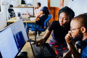 A photo of two tech professionals looking at a software program on a computer in front of them and thinking, illustrating the strategy of focusing on collaboration when answering tough interview questions about a conflict you encountered. Photo by NESA by Makers on Unsplash