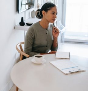 A photo of a woman with a clipboard and notebook and a skeptical expression, illustrating that some hiring managers are skeptical of pain letters as they find them arrogant.