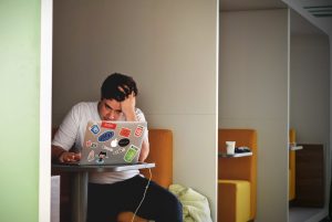 A photo of a man looking down at a laptop with a concerned expression, illustrating how doomscrolling is not helpful for one's job search. Photo by Tim Gouw on Unsplash.