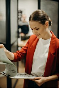 A stock photo of a woman smiling looking at resumes on a clipboard, used to illustrate what hiring managers look for when reading a resume.