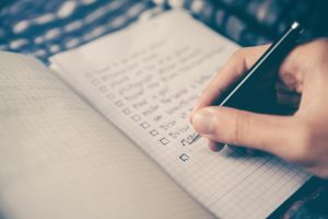Person writing checklist. Photo by Glenn Carstens-Peters on Unsplash