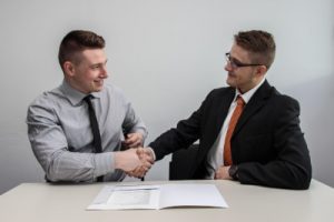 A photo of two professionally dressed men shaking hands, illustrating that you can remain on good terms with an employer after politely declining a job offer over email.