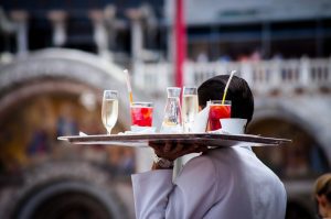 Waiter with glasses on a tray. Photo by Kate Townsend on Unsplash