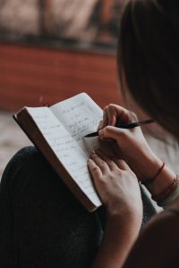 person writing out goals to determine how many resumes they need. Photo by Marcos Paulo Prado on Unsplash.