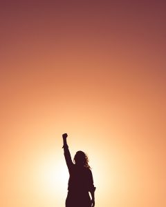 person with fist in air. Photo by Miguel Bruna on Unsplash