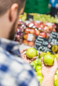 man looking at two apples