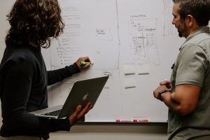 person showing diagram to person on whiteboard