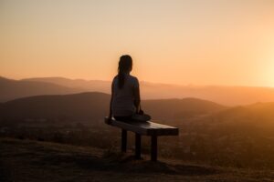 person sitting on a bench looking at mountains
