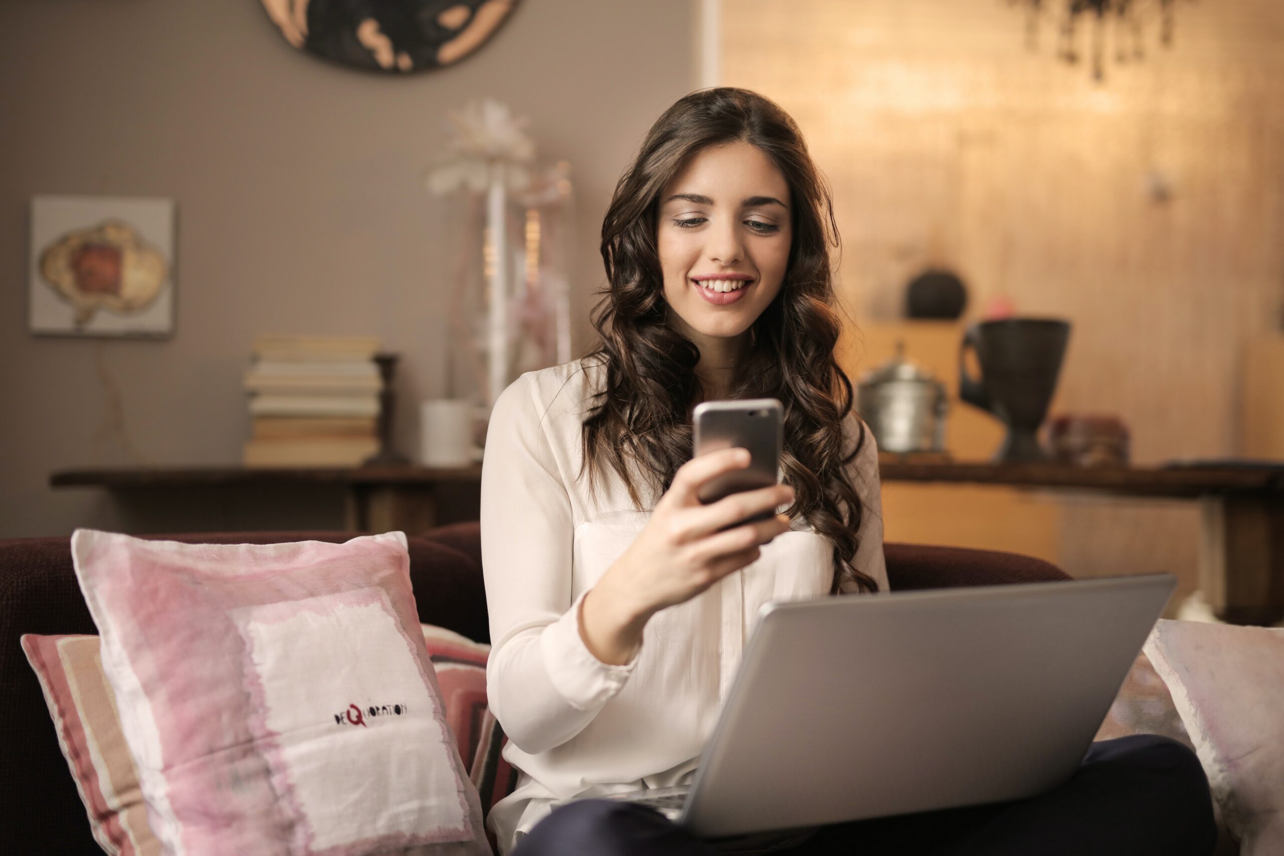 Woman looking at phone in front of laptop