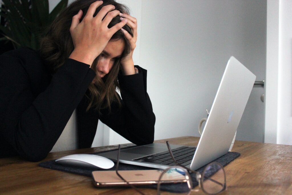 Woman looking at computer with head in hands