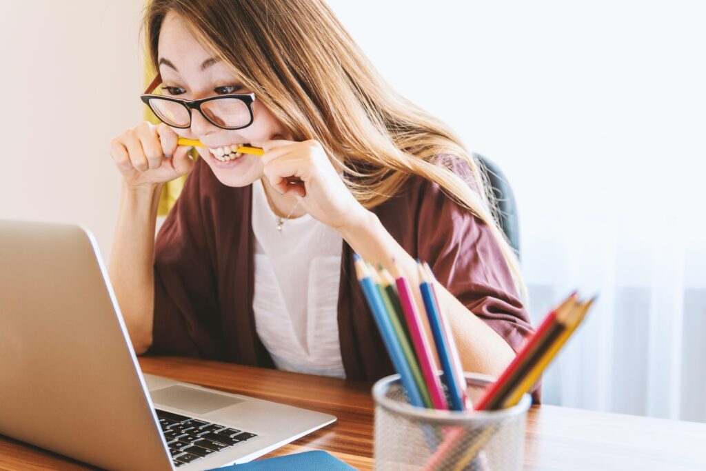 woman at a computer biting a pencil because she is frustrated with her ChatGPT cover letter