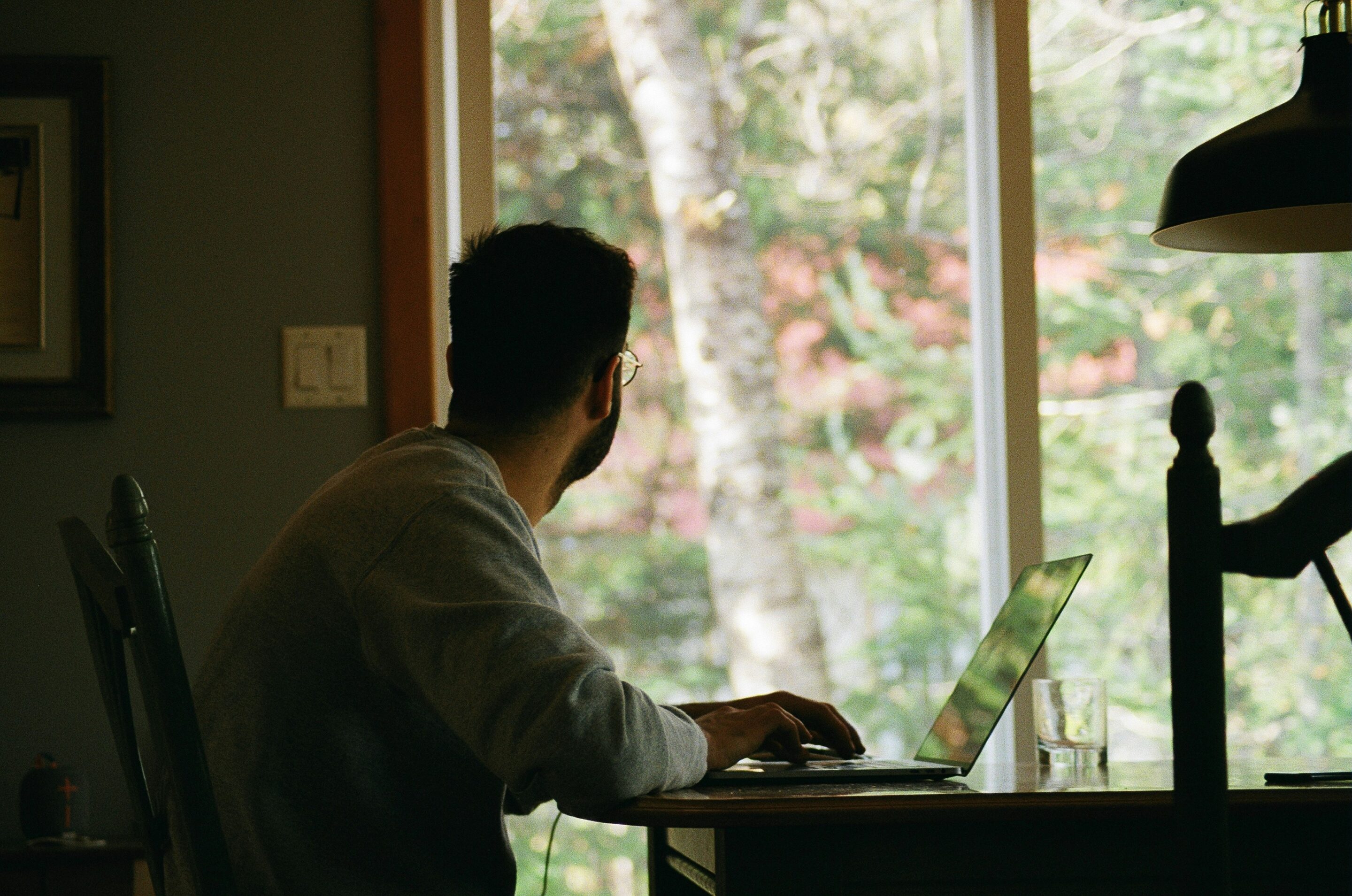 man on computer looking out window
